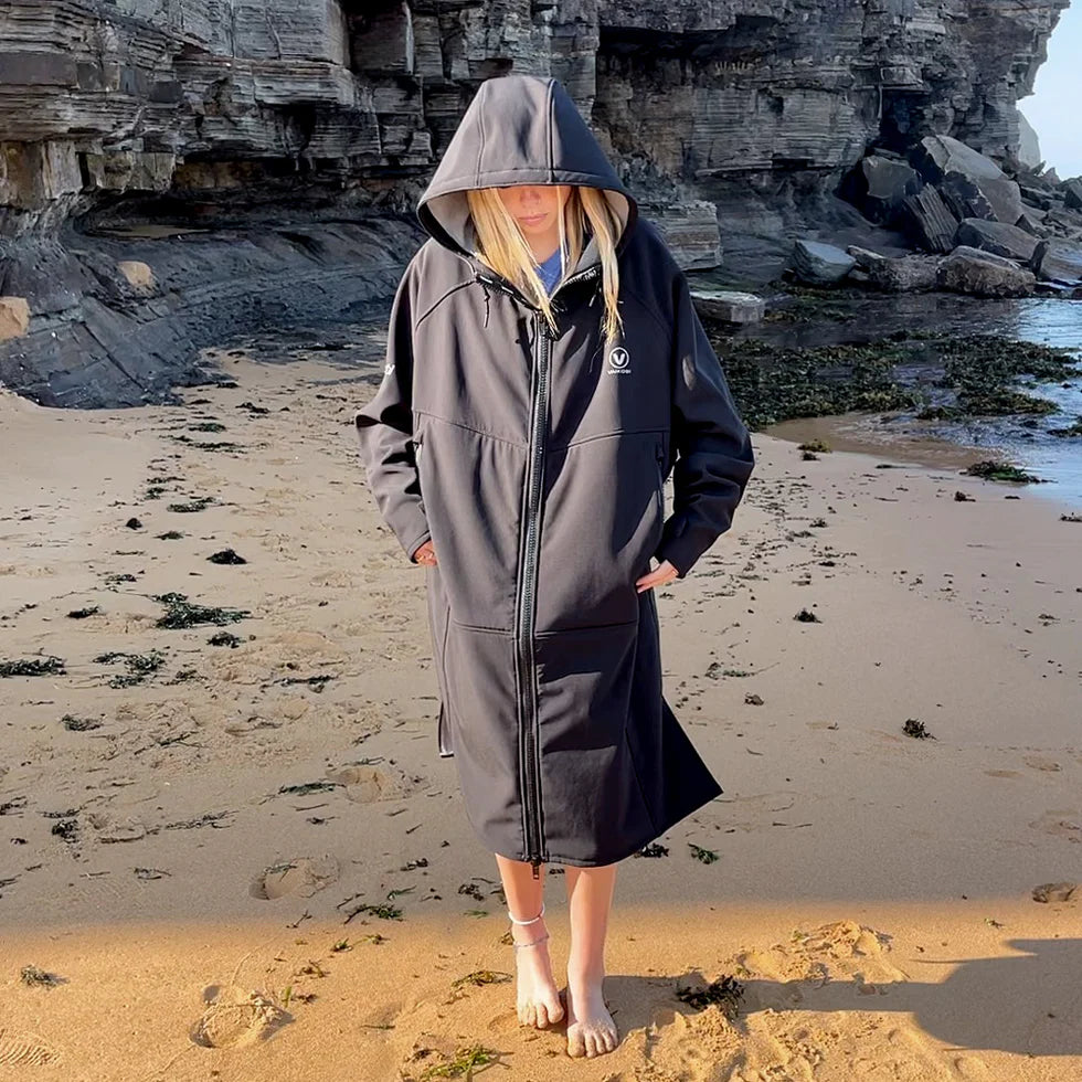 Vaikobi Beach Coat black, female model standing on beach in front of rocks